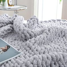 a magazine laying on top of a bed next to a pillow and blanket with an image of a woman