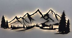 a metal wall sculpture with mountains and trees on it