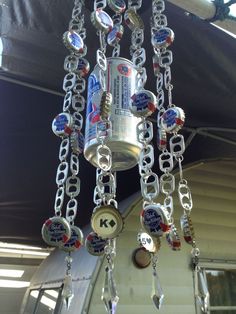 a chandelier made out of beer cans and chains hanging from the ceiling in front of a house