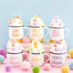 a group of coffee mugs that have bunny decorations on them and some pom poms around them