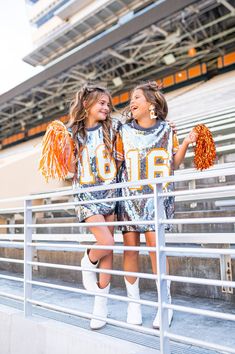 two cheerleaders standing on the bleachers holding pom poms