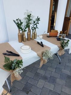 a table set up with vases and flowers on it for an outdoor wedding reception