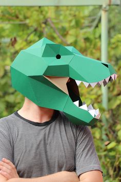 a man wearing a paper mask with a green dinosaur head on it's face