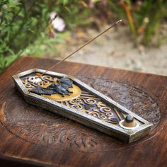 an old wooden box with a metal handle and decorative design on it sitting in front of some flowers