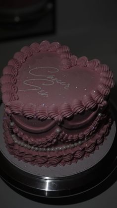 a heart shaped cake sitting on top of a metal plate with the word love spelled in cursive writing