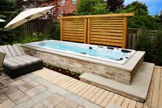 an outdoor hot tub in the middle of a backyard with patio furniture and umbrellas