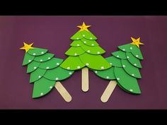 popsicle christmas trees with stars on them are cut out from green paper and placed on a purple surface