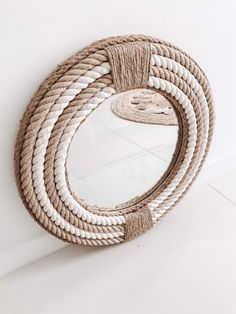 a rope mirror hanging on the wall next to a white floor with a round mirror in it