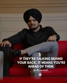 a man sitting on top of a red couch wearing a turban and black shirt