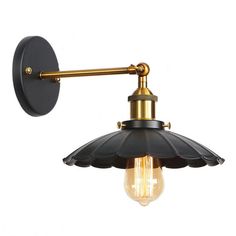 an industrial style wall light with a black and gold shade on the bulb, against a white background