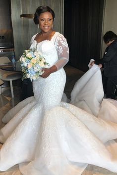 a woman in a white wedding gown holding a bouquet and posing for the camera with her dress on