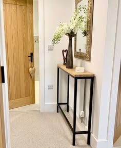 a vase with white flowers is sitting on a small table in the middle of a hallway