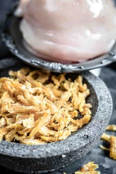 some food that is in a bowl on a table and next to it are chicken pieces