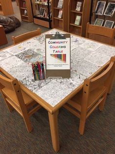 a table with some books on it in a room full of bookshelves and chairs