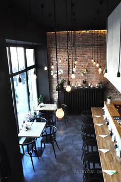 the interior of a restaurant with tables, chairs and lights hanging from the brick wall