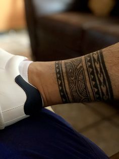 a man's arm with a tattoo on it sitting in front of a couch