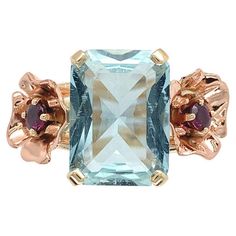 Bague rétro en or jaune 14K ornée d'une aigue-marine rectangulaire à taille brillant pesant 4,52 carats. L'aigue-marine bleu clair mesure environ 12,8 mm x 9,4 mm. Des fleurs en or rose faites à la main sont appliquées de part et d'autre avec des rubis authentiques ronds. Les rubis sont de couleur rouge rosé foncé et mesurent environ 3 mm. Les rubis pèsent environ 0,39cts au total. La bague convient à un doigt de taille 7,75 et pèse 3,74 dpt. Il date des années 1940. Aquamarine And Ruby, Rose Gold Flowers, Ruby Flower, Rose Gold Flower, Pinkish Red, Gold Cocktail Ring, Bracelet Love, Modern Ring, Aquamarine Blue