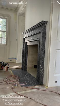 an empty room with a fireplace in the middle and wires on the floor next to it