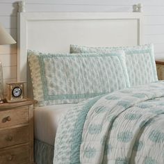 a bed with blue and white bedspread in a bedroom next to a night stand