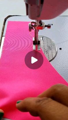 someone is using a sewing machine to sew on a pink piece of fabric that has been stitched together