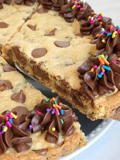 a chocolate chip cookie cake with sprinkles on it's edges and one slice cut out