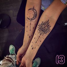 two people holding hands with tattoos on their arms and one has a sun and moon