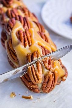 a knife cutting into a cake with pecans on it