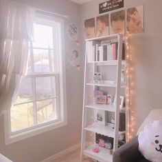 a room with a book shelf, window and stuffed animal on the floor next to it