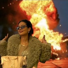 a woman with glasses is standing in front of a large explosion