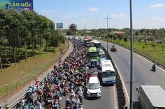 a large group of people riding bikes down the street in front of cars and trucks