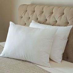 two white pillows sitting on top of a bed