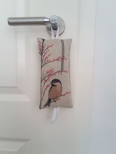 a door handle with a bird on it hanging from the side of a white door