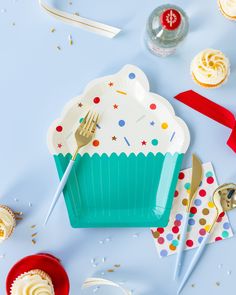 cupcakes, forks and confetti on a blue table with white frosting