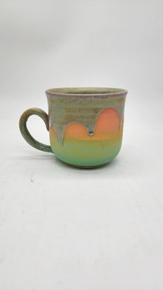 a green and orange cup sitting on top of a white table