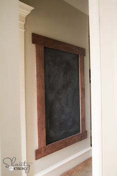 a chalkboard mounted to the side of a wall in a room with white walls