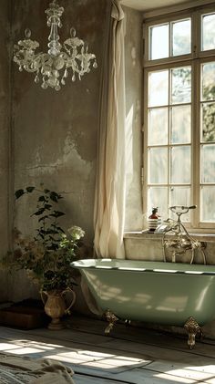 an old fashioned bathtub in front of a window with a chandelier hanging from the ceiling