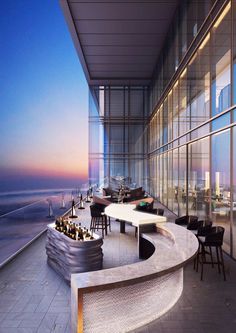 an outdoor dining area overlooking the ocean at sunset or sunrise, with tables and chairs