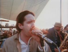 a man holding a microphone up to his mouth while standing in front of a crowd