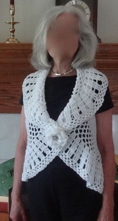 an older woman wearing a white crocheted shawl and black shirt standing in front of a mirror