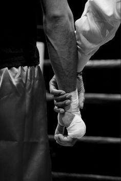 two people holding hands while standing next to each other in front of a boxing ring