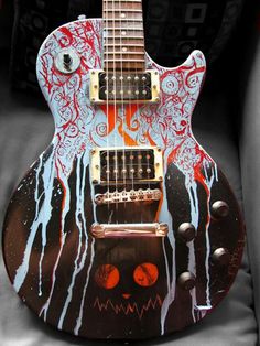 an electric guitar with red and blue paint on it