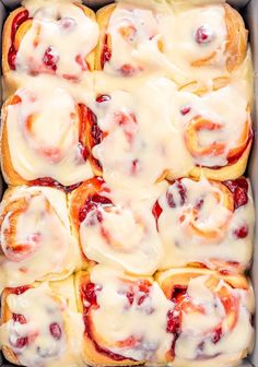 a pan filled with rolls covered in cream cheese and cranberry toppings, ready to be eaten