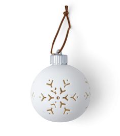 a white ornament with snowflakes hanging from a brown cord on a white wall