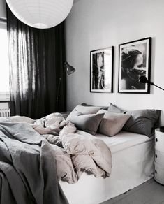 a black and white photo of a bed in a room with pictures on the wall