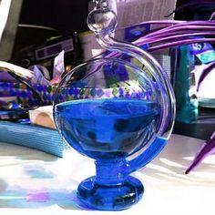 a blue glass vase sitting on top of a table next to a purple planter