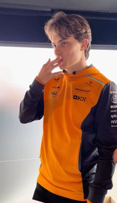 a young man in an orange and black shirt brushing his teeth