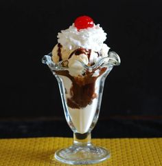 an ice cream sundae in a glass vase with a cherry on top and whipped cream