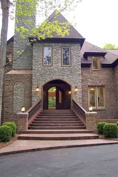 a large stone house with steps leading to the front door and entry way that leads up to it