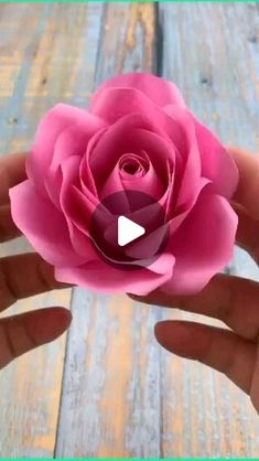 a person holding a pink flower in their hand on a wooden surface with text reading how to make paper flowers