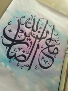 an arabic calligraphy is displayed on a piece of paper with a pen next to it